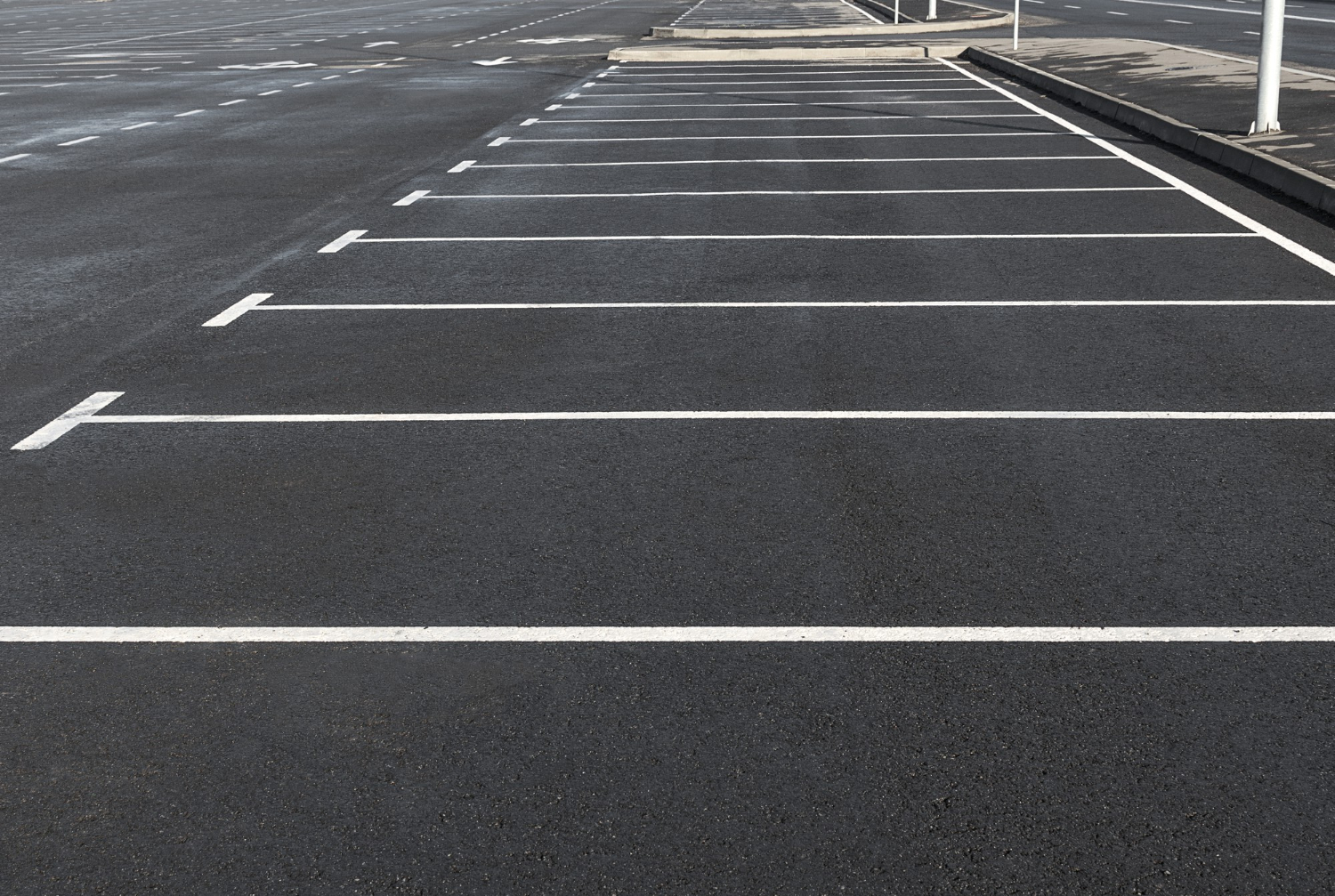Empty parking lot with neatly painted white lines marking parking spaces on smooth asphalt.