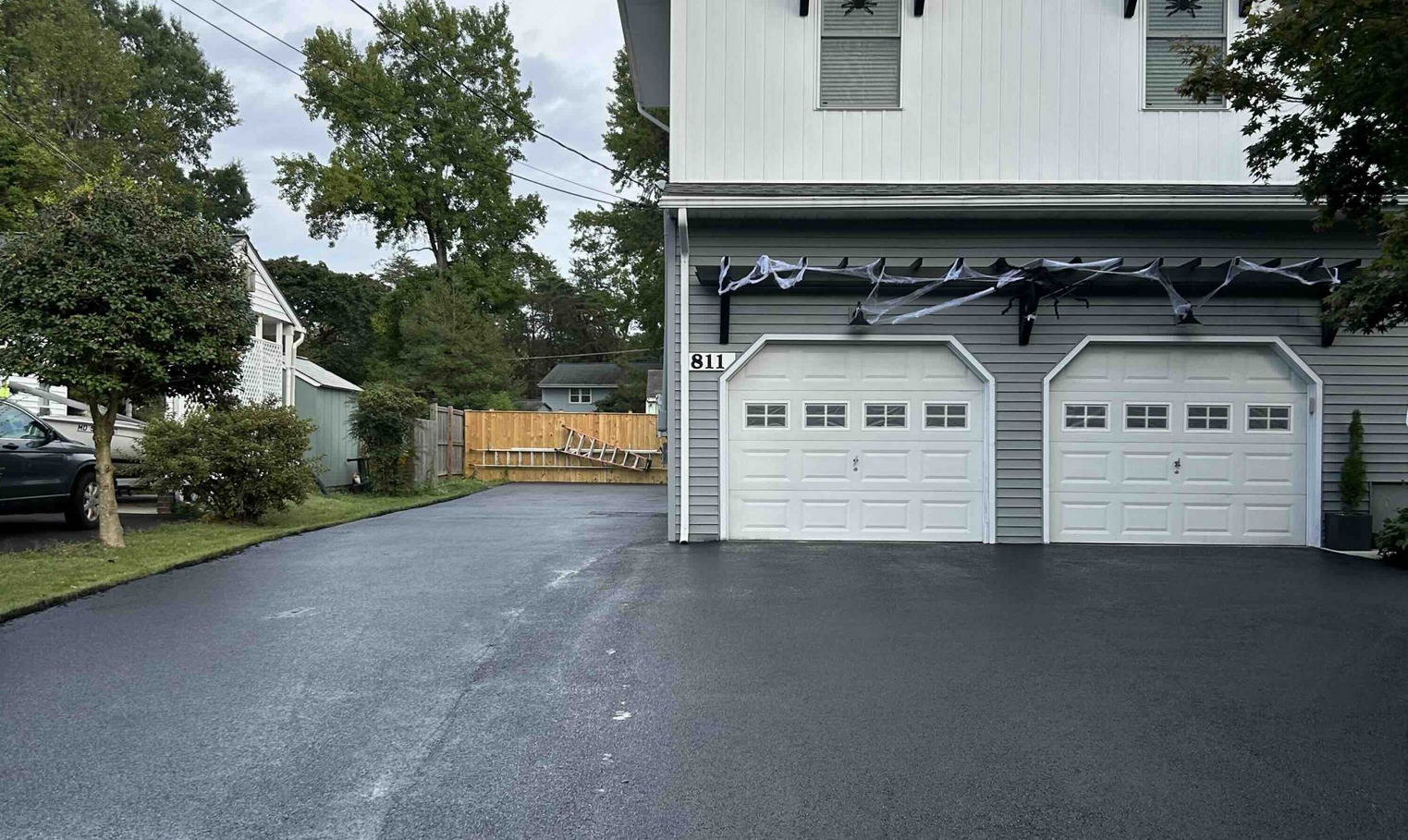 A driveway leads to a two-car garage decorated with black and white Halloween streamers above the doors.